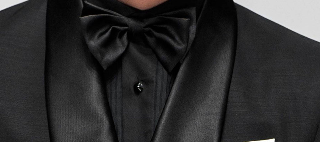 Hombre con traje negro de tres piezas, camisa negra y pajarita negra