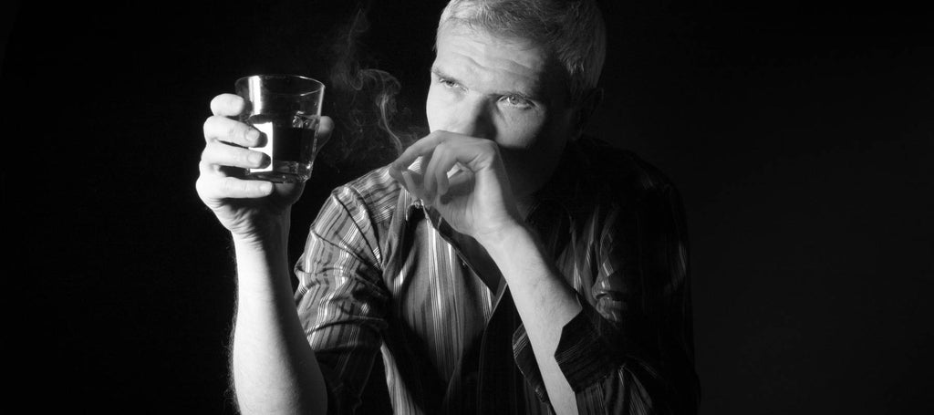 Hombre con un vaso de alcohol y camisa de rayas blancas y negras