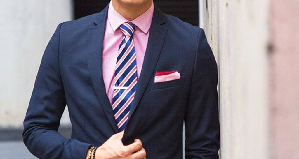Mann rosa Hemd, marineblauer Anzug, marineblaue und rosa Krawatte und goldene Krawattenklammer