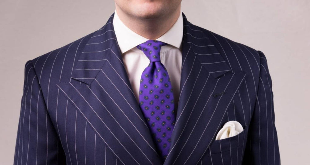 Hombre con traje y corbata púrpura con pañuelo de bolsillo y camisa blanca
