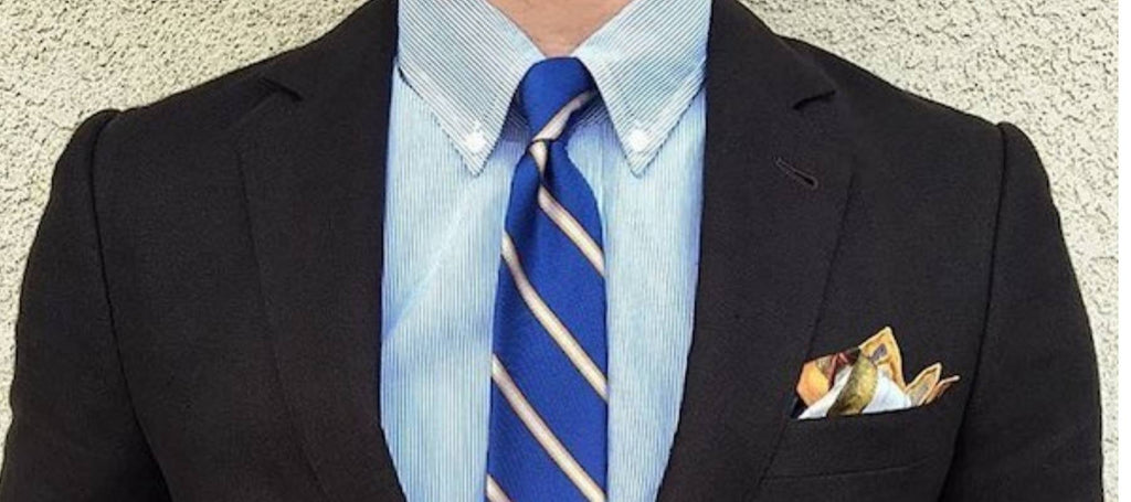 Ein Mann mit einem schwarzen Anzug, einer marineblauen Krawatte und einem hellblauen Hemd