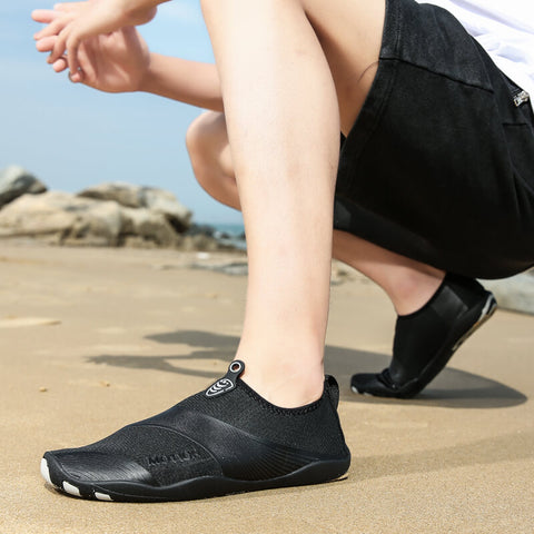 Homme avec chaussures de plage Motion Noir d'Aquashoes marchant sur le sable