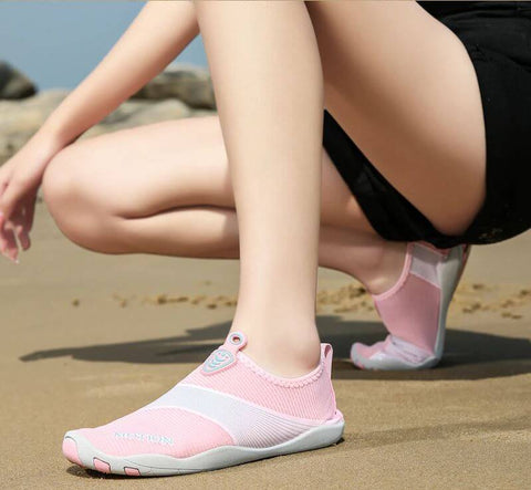 Femme avec chaussures de plage Motion Rose d'Aquashoes marchant sur le sable