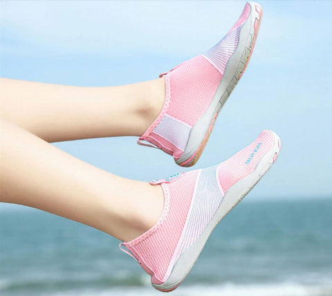 Femme avec chaussures de plage Motion Rose d'Aquashoes marchant sur le sable