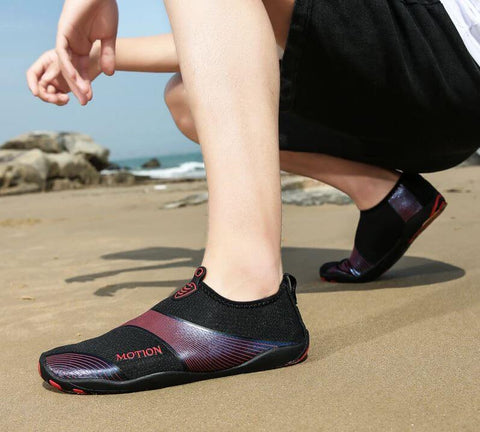 Homme avec chaussures de plage Motion Rouge d'Aquashoes marchant sur le sable