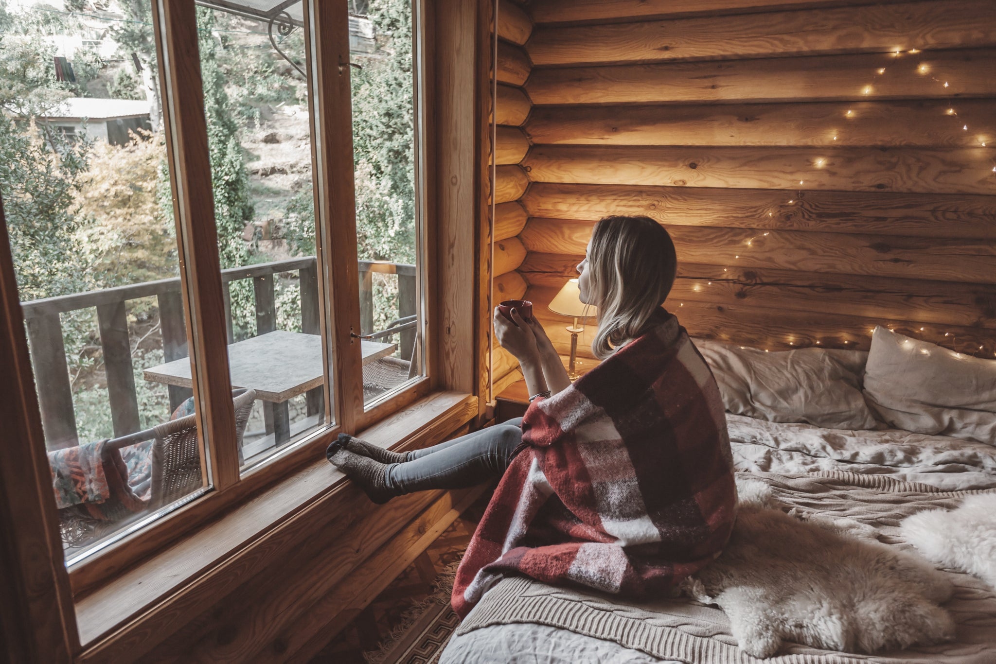 Woman drinking coffee in a Scandinavian log cabin.