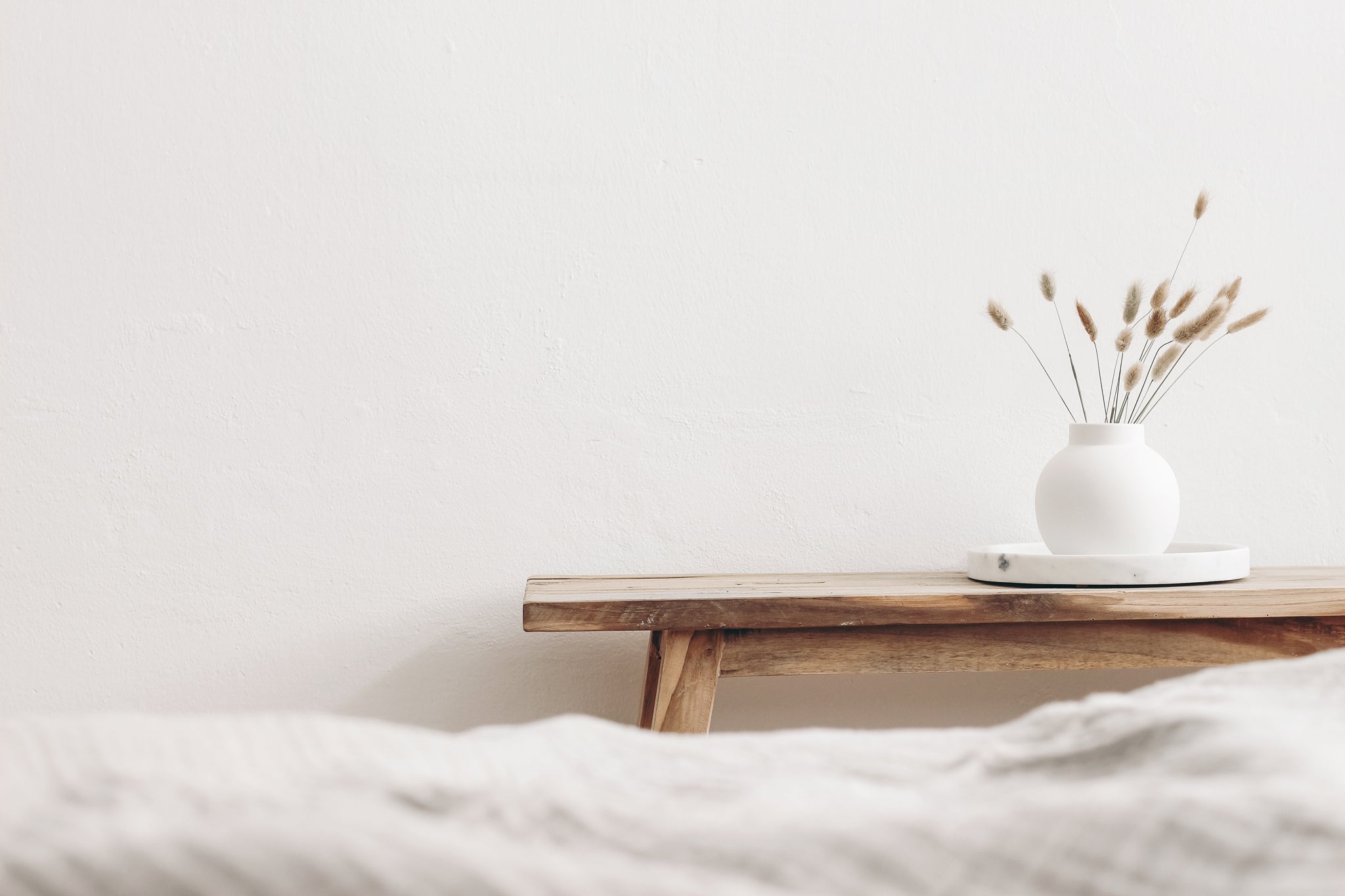 Scandinavian bedroom, a natural wooden bench with flowers & vase.