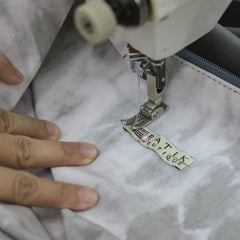 a seamstress sewing batik boutique tag onto the shirt