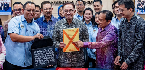 a picture of the prime minister of malaysia holding a document to be put into the batik bag made by batik boutique exclusively for the prime minister