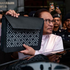 a picture of the prime minister of malaysia holding up the bag that was made specifically for him by the team at batik boutique