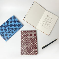 Unveil the artistry within – our batik-inspired notebooks gracefully displayed against a neutral backdrop, some invitingly opened to reveal the captivating designs adorning the inside pages