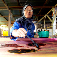 A skilled female artisan passionately engaged in the traditional method of crafting authentic batik, exemplifying the dedication and artistry inherent in this time-honored process