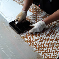 an artisan blocking in arabesque pattern onto a fabric