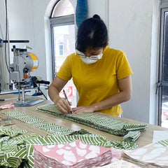 a photo of a seamstress in the middle of cutting authentic batik fabric