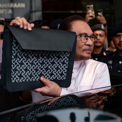 prime minister of malaysia holding up a bag made by batik boutique