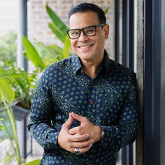 A photo features a man striking a professional pose in corporate attire, wearing a black alur patterned batik shirt, perfectly suited for a formal and professional setting