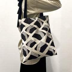 a model showcasing a tote bag in the pattern black nasi lemak made of batik
