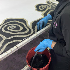 artisan in the process of coloring in authentic batik in the pattern black kerepek