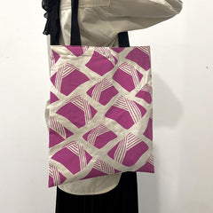 a model showcasing a tote bag made of batik in the pattern fuchsia nasi lemak