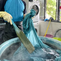 An artisan is seen boiling the fabric to melt the wax, a crucial step in the batik-making process.