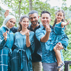 a group photo models of different ages, posing happily together while wearing authentic batik all in the pattern forest green