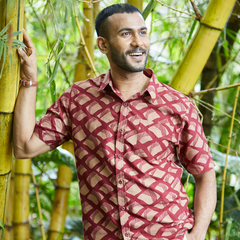 a man posing in a bamboo forest in a batik shirt in pineapple motif for batik boutique