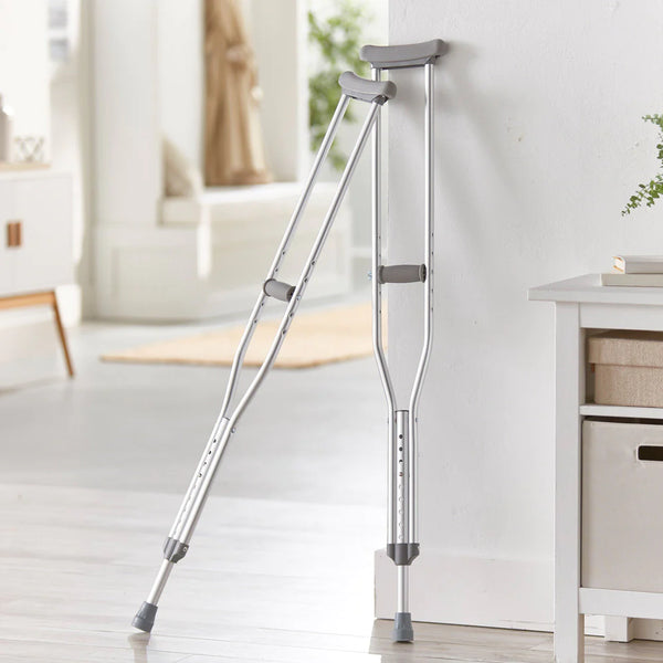 A pair of underarm crutches leaning against a wall in a house