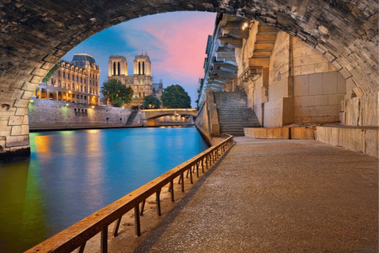 Hidden Gems in Paris Travel Guide: Walking through tunnel in the evening with the Notre Dame Cathedral in background