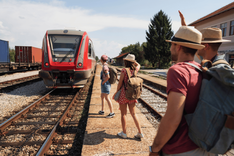 group of two men and two women boarding a red train for a European train journey adventure