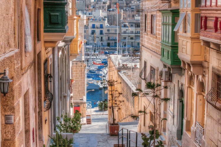 View of a street in Malta looking down at the harbour with boats. Ultimate Destination for Exploring is Malta