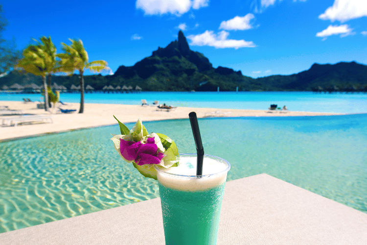 Blue cocktail next to the pool overlooking the beach and mountains in Bora Bora. Ultimate Destination for Relaxation is Bora Bora