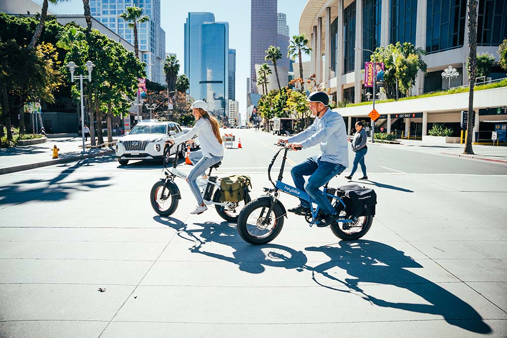 The man and the girl are riding Mars e-bikes on the city