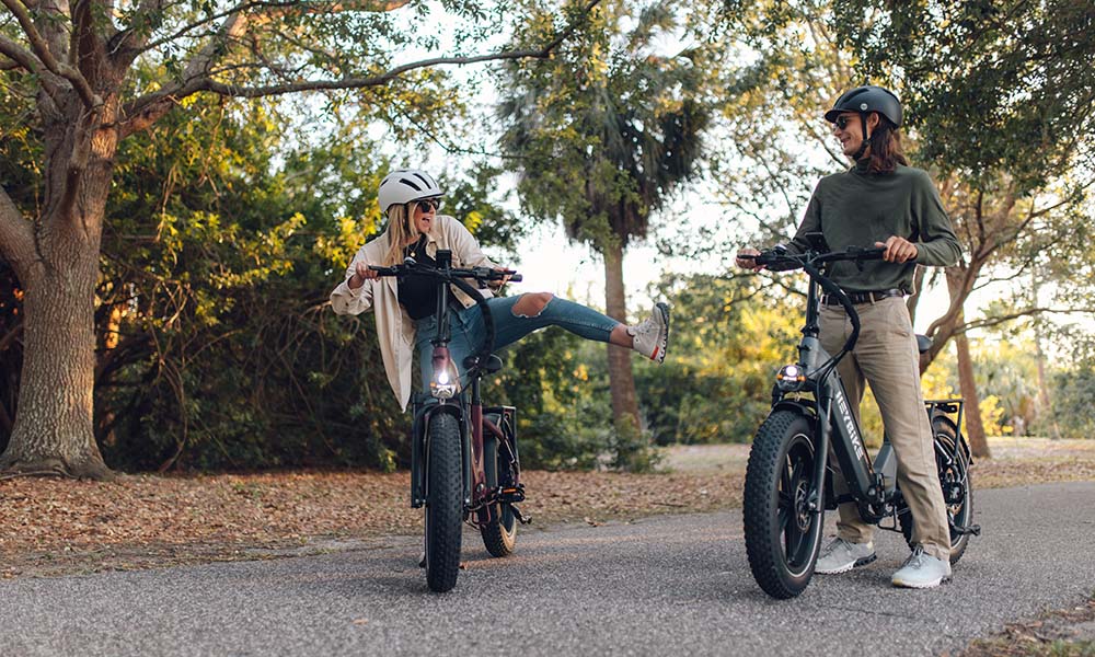 A man and a girl are riding e-bikes on the road