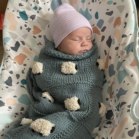 Newborn wrapped in a eucalyptus blue organic handmade baby blanket from Sheep Dreamzzz. Each hand knitted baby blanket is super soft.