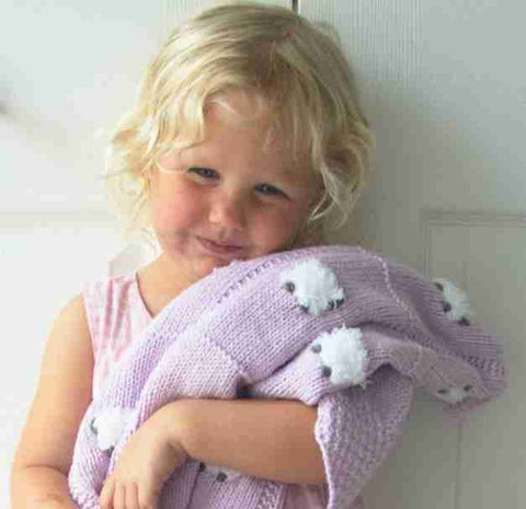 Blonde toddler girl hugging her lavender Sheep Dreamzzz kids baby blanket.