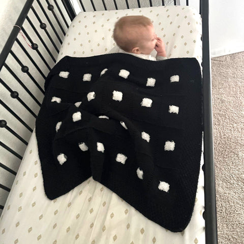 Baby in a crib under a Sheep Dreamzzz baby blanket