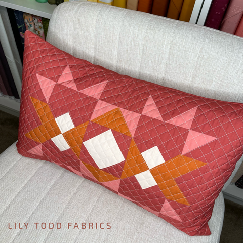 a quilted lumbar pillow in rust, orange and pink fabrics.