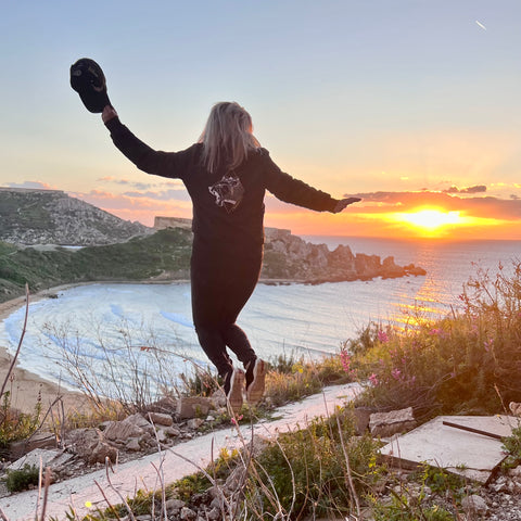 Wild Warrior Style Women in black bomber jack with wild lioness embroidery jumping up at sunset
