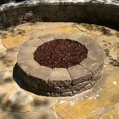 Fire pit filled with brown glass chips, surrounded by flagstone