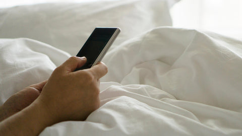 a hand with a phone with sheets in background