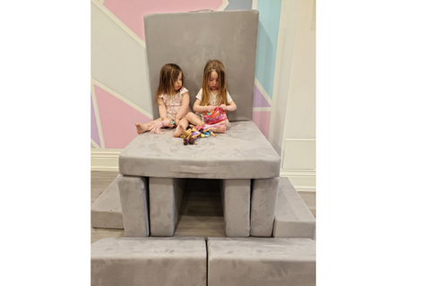two little girls sitting on a play couch built in to a chair off the ground