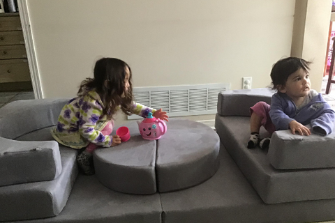 two little girls sit as restaurant booth play couch build
