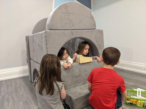 grey play couch used as a store with kids playing