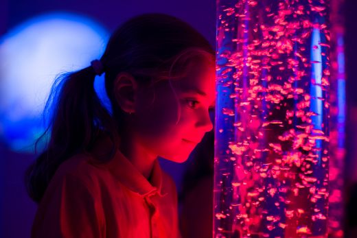 sensory room with a girl staring into a moving light. the room has a red glow.