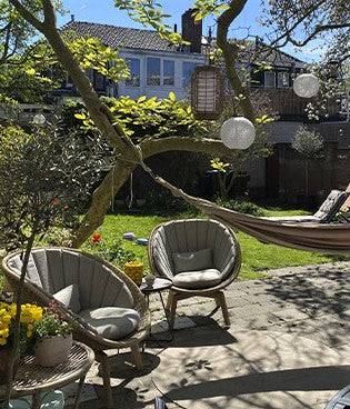 Two lounge chairs in the garden, green grass, lantern lamps