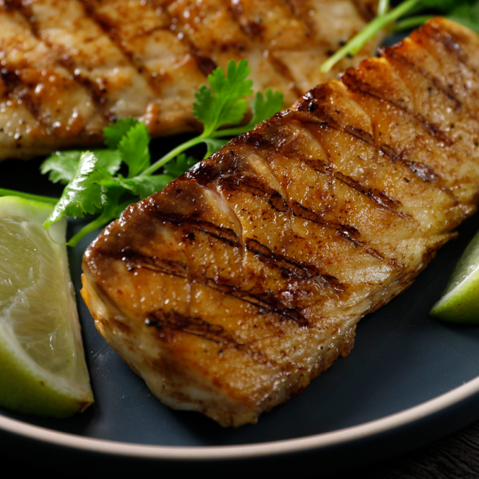 Grilled Cobia fish fillets on a plate with a lime.