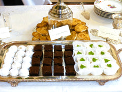 A silver tray filled with petit fours, brownies, and tea cakes.