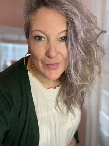 close up selfie of woman in her 40s with purplish white hair that's wavy