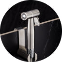 Handheld bidet mounted on a sleek black marble bathroom wall.