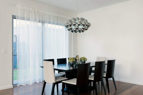 Sala de jantar com lustre prateado em cima da mesa